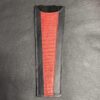 A red and black leather case is sitting on the ground.