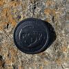 A black button on the side of a rock.