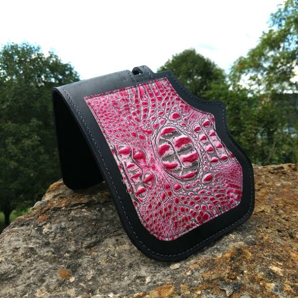 A pink and black wallet sitting on top of a rock.