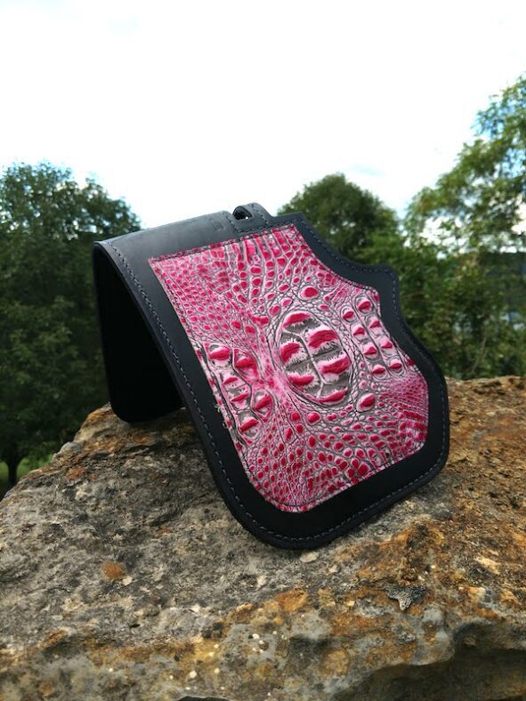 A pink and black wallet sitting on top of a rock.