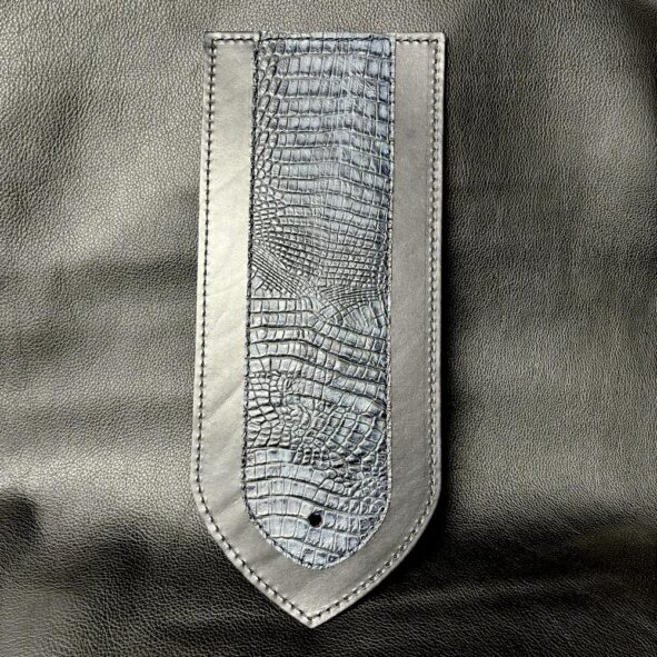 A leather bookmark with silver trim and a snake skin pattern.