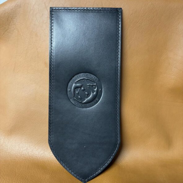 A black leather tie with a round emblem on it.